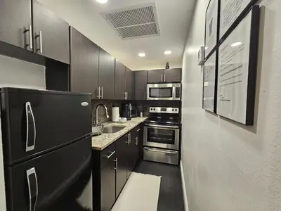a kitchen with wooden cabinets and a black refrigerator at Nice 2 bedrooms near the beach in Miami Beach