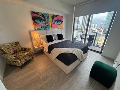 a bedroom with a bed and a chair and a large window at Spectacular corner 2BDR Downtown Miami in Miami