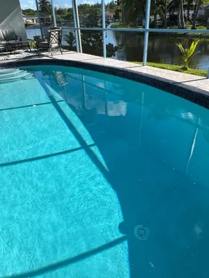 a swimming pool with blue water in front of a building at 4bdrm Waterfront salt water Pool home with Outdoor theater Game Rm Make up vanities in every room Perfect for Game days and concerts trips to Miami Hard rock stadium and hotel 15 mins away in Miramar