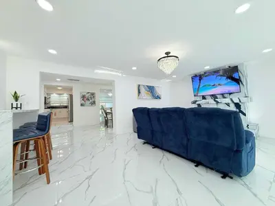 a living room with a blue couch and a television at Ultimate Getaway Private Pool & Games Near Beach in Fort Lauderdale