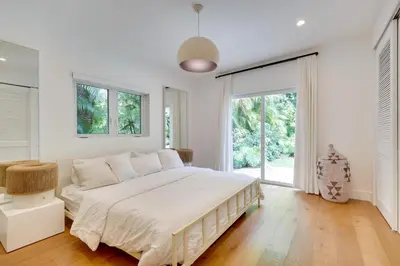 a white bedroom with a large bed and large windows at Biscayne Park Urban Oasis with Lush Backyard! in Biscayne Park