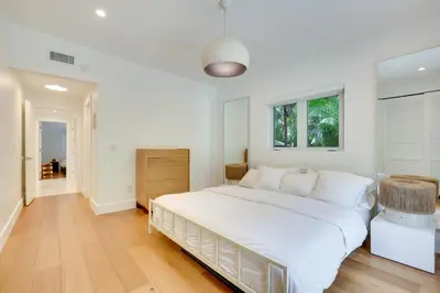 a white bedroom with a large bed and a window at Biscayne Park Urban Oasis with Lush Backyard! in Biscayne Park