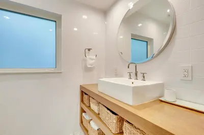 a white bathroom with a sink and a mirror at Biscayne Park Urban Oasis with Lush Backyard! in Biscayne Park