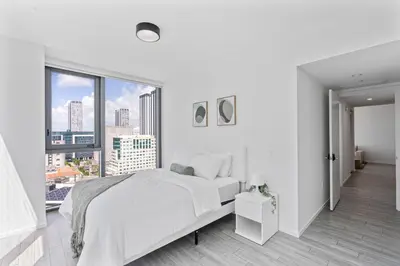a white bedroom with a bed and a large window at Downtown Miami Luxe Studio Suite in Miami