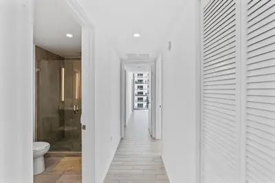 a hallway with white walls and a bathroom with a toilet at Downtown Miami Luxe Studio Suite in Miami