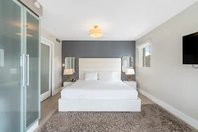 a bedroom with a white bed and a flat screen tv at Spacious Studio with Roof Top Pool & Bar in Miami Beach