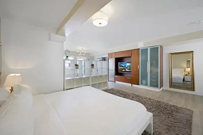 a white bedroom with a large bed and a television at Spacious Studio - Roof Top Pool & Bar South Beach in Miami Beach