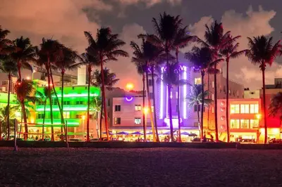 a city with palm trees and a building with lights at Ocean Drive Studio with Rooftop Pool Prime Location in Miami Beach