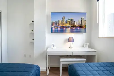 a bedroom with a desk and a picture of a city at Large Apt, Parking, Split King Bed, Washer & Dryer in Miami
