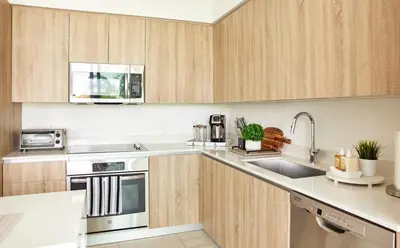 a kitchen with wooden cabinets and stainless steel appliances at Stylish 2BR Quadro Luxe Stay in Design District in Miami