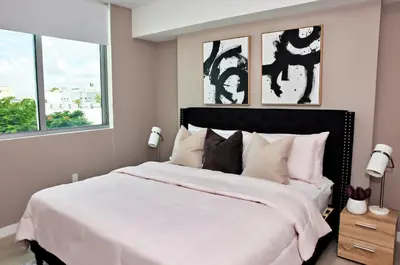 a bedroom with a large white bed with two windows at Stylish 2BR Quadro Luxe Stay in Design District in Miami