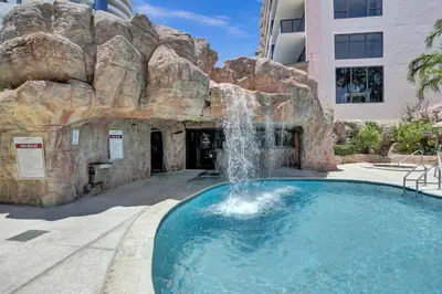 a swimming pool with a waterfall in front of a building at Oceanside Paradise Escape Spacious and Scenic Resort amenities Pools Bar Sauna 1514 in Miami Beach
