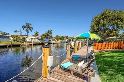 a dock with chairs and an umbrella on a body of water at Waterfront Retreat Home Dania Beach in Dania Beach