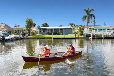 two people are rowing a boat in the water at Waterfront Retreat Home Dania Beach in Dania Beach