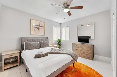 a bedroom with a bed with a ceiling fan and a television at Modern 3 BR Villa Near Beach & FLL in Hollywood