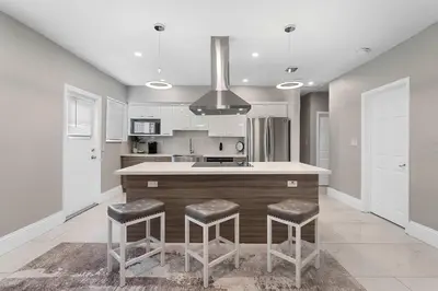 a kitchen with a counter and stools in it at Modern 3 BR Villa Near Beach & FLL in Hollywood