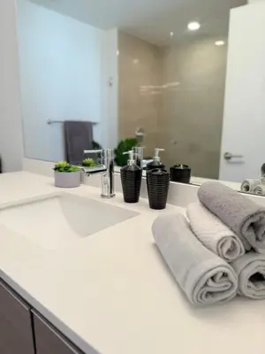 a bathroom with a sink with towels and a mirror at Luxury Pent House Suite with Downtown Views in Miami