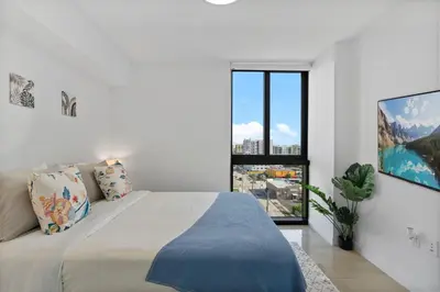 a white bedroom with a large bed and a window at Luxury Pent House Suite with Downtown Views in Miami