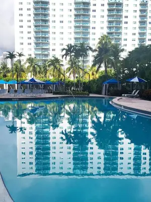 a large swimming pool with palm trees and buildings at Luxury Beach & City View Condo 5 min walk to beach in Sunny Isles Beach