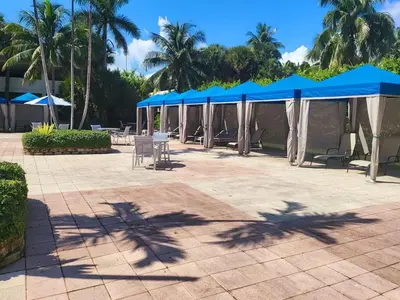 a patio with blue umbrellas and tables and chairs at Luxury Beach & City View Condo 5 min walk to beach in Sunny Isles Beach