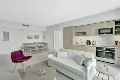 a living room with a white couch and a kitchen at 40th floor lux condo with pool, gym and spa access in Miami