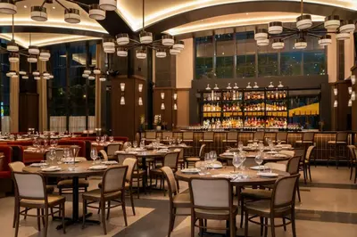 a dining room with tables and chairs and a bar at 40th floor lux condo with pool, gym and spa access in Miami