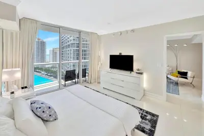 a white bedroom with a large bed and a television at Icon Brickell 20th Floor 1BR Pool View Balcony in Miami