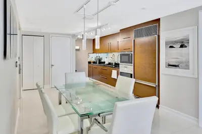 a dining room with a glass table and white chairs at Icon Brickell 20th Floor 1BR Pool View Balcony in Miami