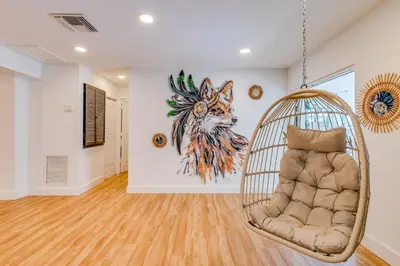 a swinging chair in a room with a painting on the wall at Fox Garden Luxury Boho Near Downtown & Beach in Fort Lauderdale