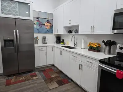 a kitchen with white cabinets and a stainless steel refrigerator at Little Wynwood Oasis in Miami