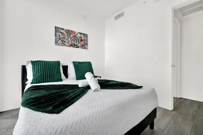 a bedroom with a large bed with green and white sheets at Ocean Front Condo Near Cruise Port, Bayfront Park, plus Free Parking in Miami