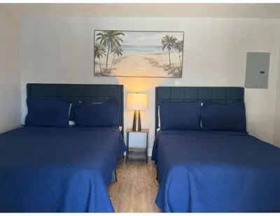 two beds in a room with blue sheets and a lamp at Studios & Coral Gable, close to downtown and airport in Miami