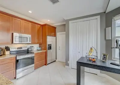 a kitchen with wooden cabinets and a black counter top at Family house with Heated Pool, Walk to Dining in Fort Lauderdale