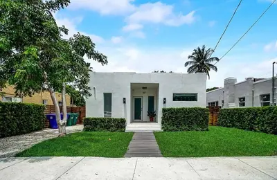 a white house with a yard with a driveway at Stylish Miami Getaway in Miami
