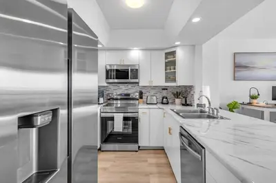 a kitchen with white cabinets and a stainless steel refrigerator at Elara Beachfront 2 Bedrooms Direct OceanView with Parking in Miami Beach