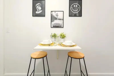 a table with two stools in front of a white wall at Coastal Studio Stay Near the Beach in Miami