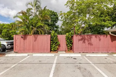 a red fence in a parking lot with trees at Your Modern South Florida Oasis Comfy and Central in Fort Lauderdale