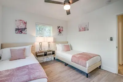 two beds in a room with white walls and wooden floors at Friendly Fox Luxury Pool & Spa House Near Downtown & Beach in Fort Lauderdale