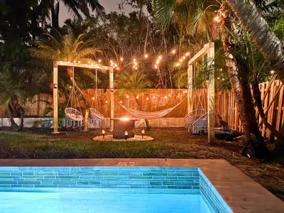 a backyard with a hammock and a pool at night at Friendly Fox Luxury Pool & Spa House Near Downtown & Beach in Fort Lauderdale