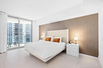 a white bedroom with a large bed and a large window at Oceanfront Luxe Apt 24th Floor in Hollywood
