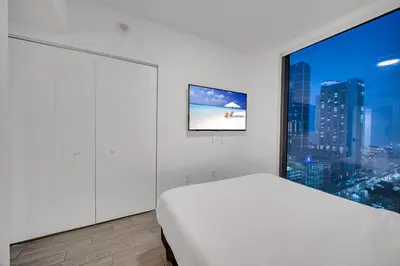 a bedroom with a white bed and a large window at High Floor Unit Heart Of Miami with pool and gym in Miami