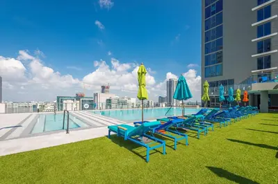 a row of lounge chairs with umbrellas and a pool at High Floor Unit Heart Of Miami with pool and gym in Miami