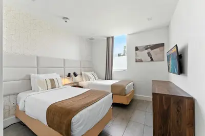 a hotel room with two beds and a tv at Modern South Beach 2 Bedroom Gem in Miami Beach