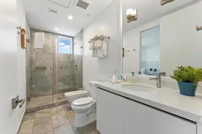 a bathroom with a toilet and a sink and a shower at South Beach Sleek 2BR Getaway in Miami Beach