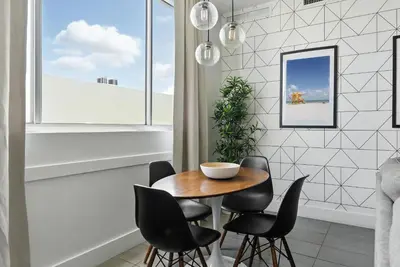 a dining room with a wooden table and black chairs at South Beach Sleek 2BR Getaway in Miami Beach
