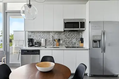 a kitchen with white cabinets and a wooden table at SoBe 2 Bedroom Near Ocean Drive in Miami Beach