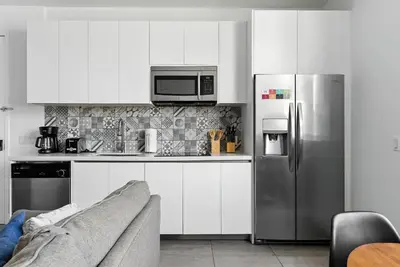a kitchen with white cabinets and a stainless steel refrigerator at South Beach 2BR Paradise in Miami Beach