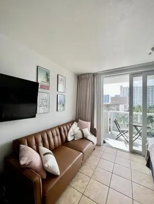 a living room with a brown leather couch and a balcony at Pet Friendly Studio Beach and Pool Access, gym ! in Sunny Isles Beach