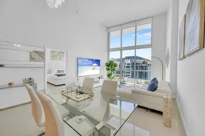 a white living room with a glass table and chairs at 40th floor High Ceilings unit at icon brickell in Miami