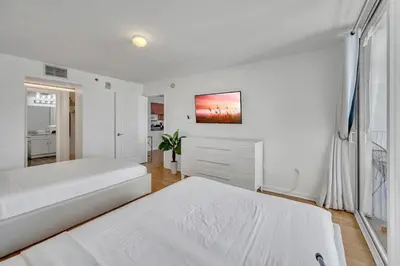 a white bedroom with two beds and a window at Superb private unit with amenities and parking in Miami